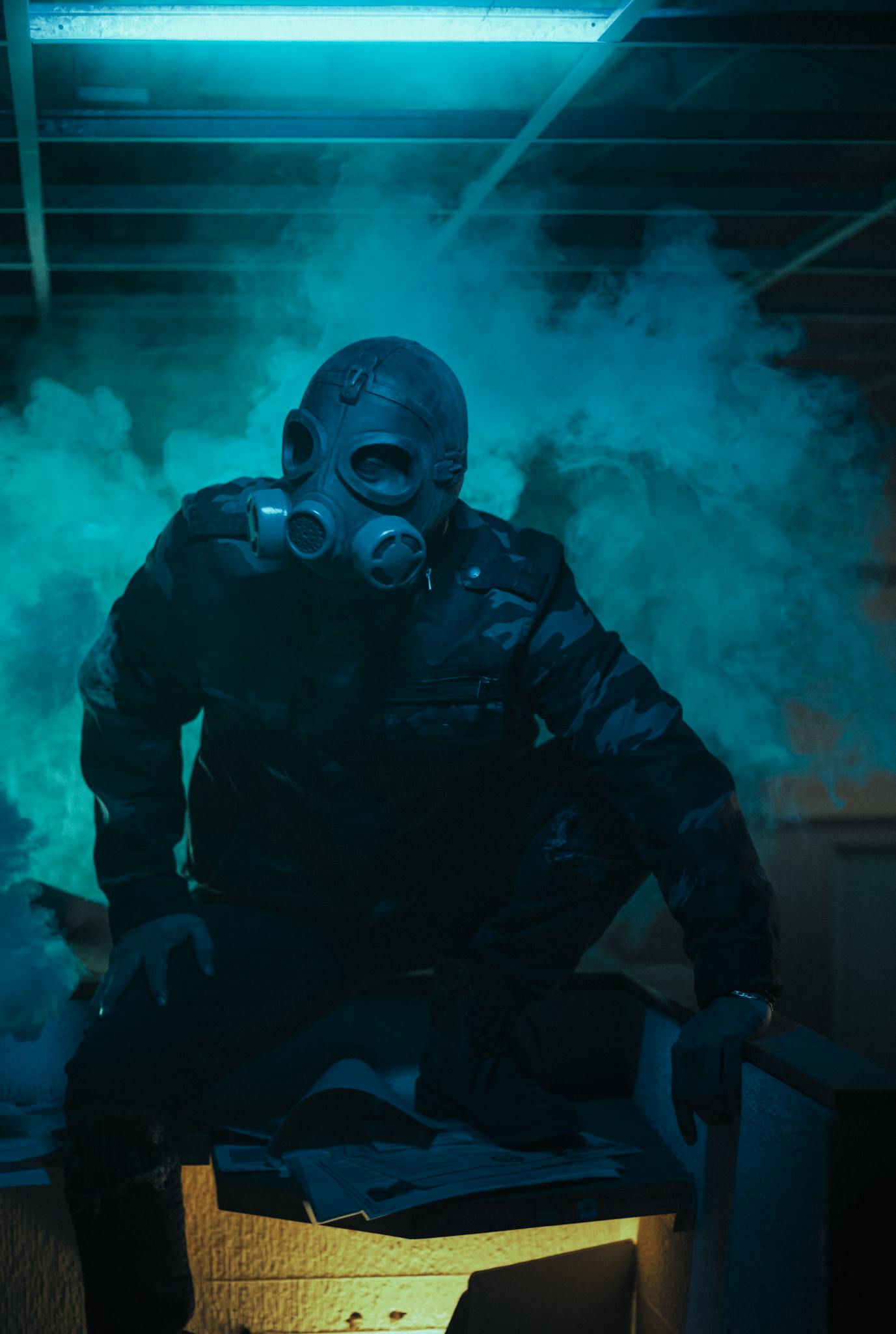 An enigmatic individual wearing a gas mask surrounded by dramatic smoke and lighting.