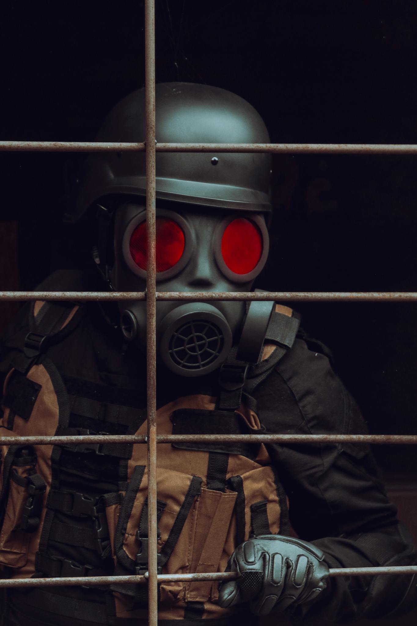 Individual wearing a gas mask and helmet, holding a bar, evoking a tactical or post-apocalyptic scenario.
